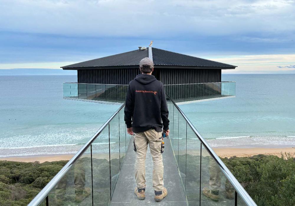 Clements Electrics electrician standing in front of the iconic Pole House in Fairhaven on the Great Ocean Road